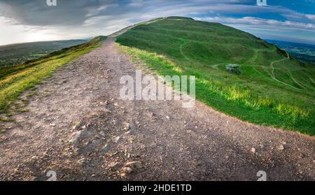 Au-dessous de Worcestershire Beacon, le soleil d'été se lève un matin d'été chaud, la lumière du soleil brille sur un sentier de randonnée de stoney qui traverse le p de Malvern Banque D'Images