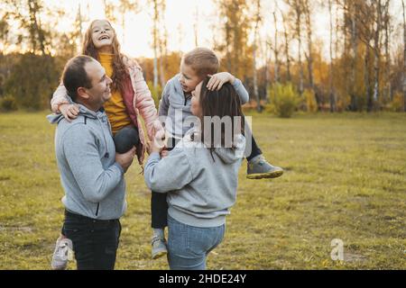 Parents heureux avec enfants jouant dans le parc.Aimez votre famille.Quatre membres. Banque D'Images