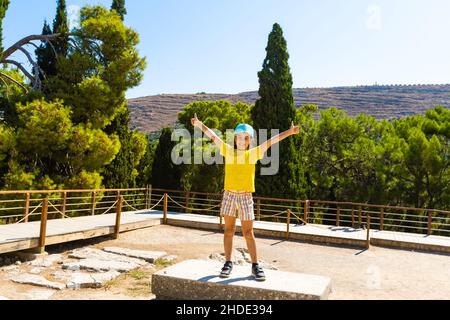 Une petite fille s'arrête pour prendre une photo d'œuvres d'art sur les murs du palais minoen à Knossos. Crète, Grèce Banque D'Images