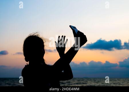 Silhouette d'une femme prenant un selfie au coucher du soleil Banque D'Images