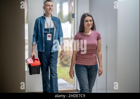 Femme et homme avec le cas marchant dans la maison Banque D'Images