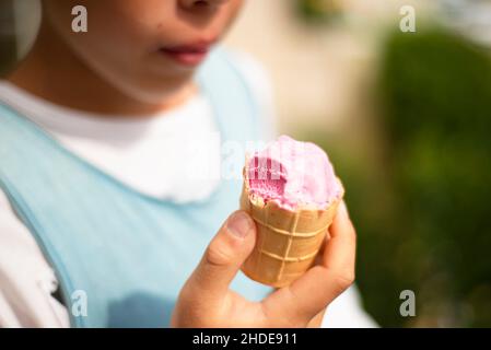 Crème glacée à la fraise dans les mains d'un garçon. Banque D'Images