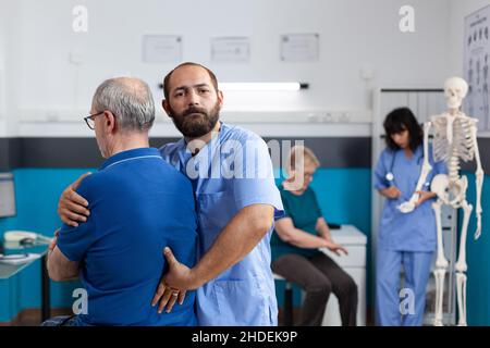 Chiropraticien traitant les lésions de la colonne vertébrale et les douleurs dorsales de l'homme âgé pour la physiothérapie.Assistant aidant le patient âgé avec une blessure pour récupérer, donnant un massage chiropratique pour la réadaptation Banque D'Images