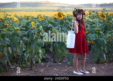 Préadolescents avec couronne dans un champ de tournesols porte une bouteille de lait Banque D'Images