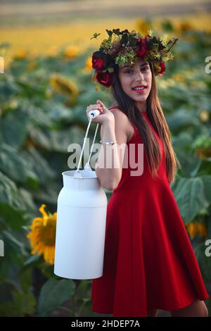 Préadolescents avec couronne dans un champ de tournesols porte une bouteille de lait Banque D'Images