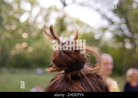 Adorable petite fille nouant des bandes élastiques sur des queues de pin Banque D'Images