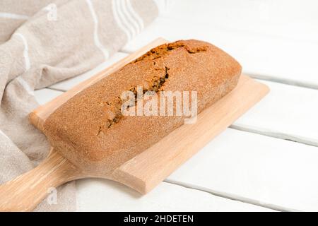 Tranches de pain au levain maison sur planche à découper en bois sur table blanche, mise au point sélective Banque D'Images