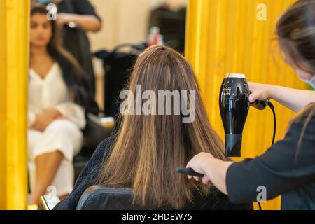 Sèche-cheveux à l'air libre.Travail du maître dans un salon de coiffure en gros plan.Le concept de beauté et de style. Banque D'Images