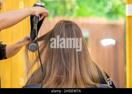 Sèche-cheveux à l'air libre.Travail du maître dans un salon de coiffure en gros plan.Le concept de beauté et de style. Banque D'Images