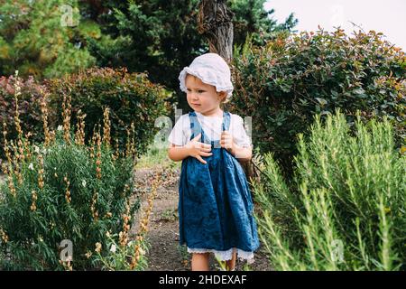 Petite fille marche dans le jardin parmi de belles plantes vertes du sud Banque D'Images