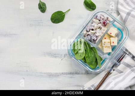 Panier-repas composé d'une salade waldorf aux pommes et aux épinards et d'un fromage en cubes dans un récipient en verre.Régime végétarien sain. Banque D'Images