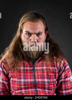 Portrait d'un homme en colère avec de longs cheveux regardant l'appareil photo. Banque D'Images