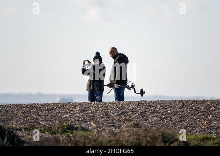 Détacher.Un couple avec un détecteur de métal sur la plage de Hayling Island, Hampshire, Royaume-Uni Banque D'Images