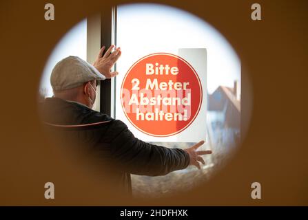 Bielefeld, Allemagne.06th janvier 2022.Un concierge tient un panneau « Veuillez garder 2 mètres de distance » à la fenêtre dans une salle de classe de l'école secondaire Max Planck pour le photographe.Les opérations scolaires sont confrontées à des défis majeurs pendant la crise de Corona.Les mesures comportementales, les mesures d'hygiène et de protection, la ventilation, le port de la protection bouche-nez et les cas de quarantaine doivent être gérés de façon continue.Credit: Friso Gentsch/dpa/Alay Live News Banque D'Images