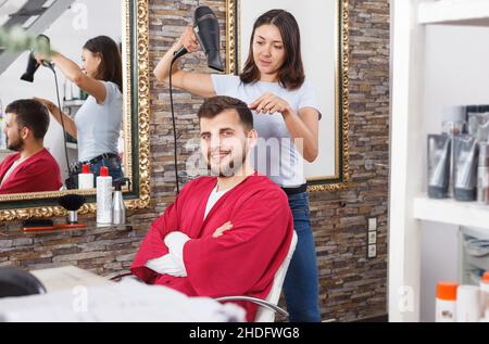 Fille professionnel coiffeur coiffeur coiffeur et séchage cheveux avec fen de l'homme Banque D'Images