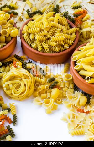 Non cuit, sec divers types de pâtes dans une casserole de céramique sur la surface blanche, image verticale Banque D'Images