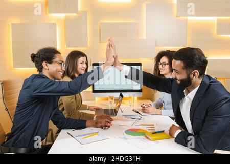 Vue latérale sur toute la longueur les hommes d'affaires sortants donnent cinq hauts lorsqu'ils travaillent avec des ordinateurs portables au bureau.Les hommes heureux pendant le travail avec le concept de technologie Banque D'Images