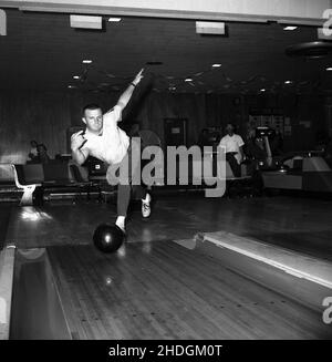 1960, historique, à l'intérieur d'une salle de bowling à dix quilles, un homme adulte roulant une balle dans une voie, Columbia, États-Unis, montrant un bon équilibre et la technique.Vu sur la gauche, est la gouttière ou le canal, une zone en forme de creux, où les boules mal placées finissent vers le haut.Dans les 1950s et 60s, un passe-temps populaire de lésiure aux États-Unis, tenpin était également un sport de compétition, avec une structure de ligue organisée et compétitive, avec des équipes hommes et femmes.La Professional Bowlers Association of America (PBA) a été fondée en 1958. Banque D'Images