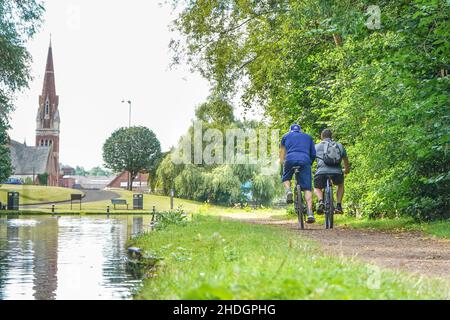 Vue arrière de deux cyclistes en vélo le long d'un sentier de remorquage sur le canal britannique en été. Banque D'Images