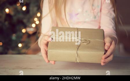 Les mains des filles tiennent une boîte cadeau pendant les fêtes de Noël et du nouvel an en hiver Banque D'Images