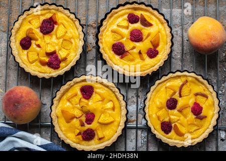 Tartelettes de crème anglaise d'été avec pêches et framboises.Vue de dessus. Banque D'Images