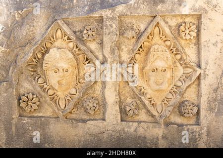 Des faces coupées en pierre à moitié effacées sur les ruines d'un bâtiment dans l'ancienne ville de Mira, Turquie Banque D'Images