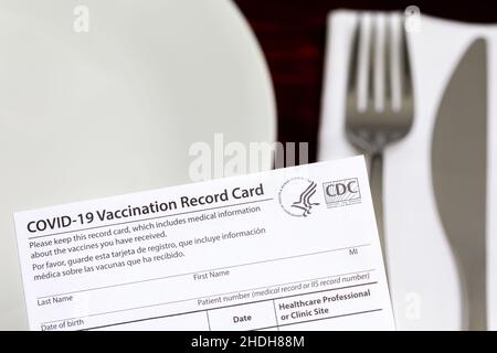 Carte de vaccination Covid-19 et table de restaurant.Mandat de vaccination à l'intérieur, restrictions de divertissement et concept d'exigence de vaccination. Banque D'Images