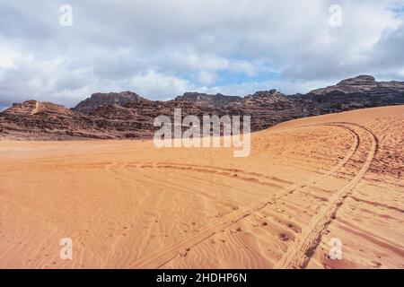 Massifs rocheux dans le désert rouge, traces de véhicules dans le sable, paysages typiques à Wadi Rum, en Jordanie Banque D'Images