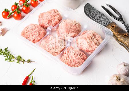 Boulettes de dindon crues dans un plateau jetable en plastique, sur fond de table en pierre blanche Banque D'Images