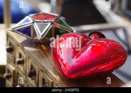 Un gros plan d'un jouet en verre en forme de coeur pour arbre de Noël sur une boîte en bois Banque D'Images