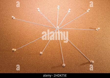 Un tableau de preuve en liège avec plusieurs cordes du point central allant vers les broches autour du tableau. Banque D'Images