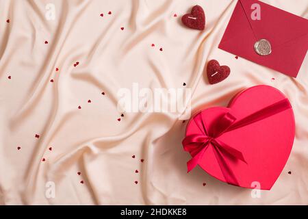 Bonne composition de la Saint Valentin.Plat déposer la boîte en forme de coeur avec des chocolats, coeur rouge, enveloppe sur fond de soie. Banque D'Images