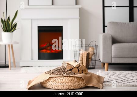 Bois de chauffage avec granulés de bois sur pouf dans la salle de séjour Banque D'Images