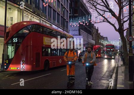 Londres, Royaume-Uni.6th janvier 2022.Deux hommes vêtés de vêtements de haute visibilité roulent en e-scooter le long d'Oxford Street tandis que les bus et les taxis se dirigent dans l'autre direction.Credit: Anna Watson/Alay Live News Banque D'Images