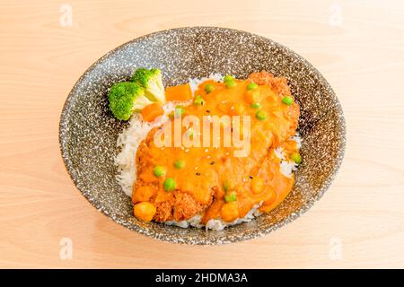Filet de poulet pané frit sur du riz blanc cuit, des pois verts et des légumes et beaucoup de curry rouge Banque D'Images