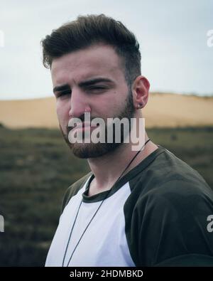 Portrait d'un jeune garçon caucasien avec un t-shirt imprimé militaire sur fond sombre Banque D'Images