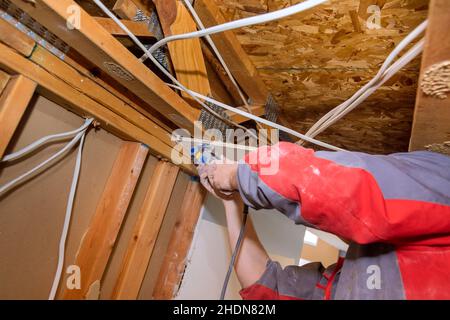 Maison dommages intérieurs pour panneau de cloison sèche avec réparation de la maison de homme coupant un placoplâtre à l'aide d'outils électriques à main couangulaires Banque D'Images