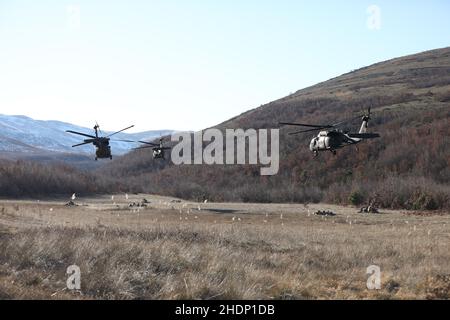 Armée américaine UH-60L Blackhawks appartenant à Une compagnie, 1st Bataillon 169th Aviation Regiment décollage d'une zone d'atterrissage tandis que les troopeurs appartenant au 1st Escadron 172nd Cavalry Regiment (Mountain) tirent la sécurité dans la zone d'entraînement de Babaj Boks, Kosovo le 21 décembre 2021.Les soldats participaient à 'Alpine Swale', un exercice d'entraînement visant à maintenir la disponibilité pour toutes les éventualités tout en améliorant l'interopérabilité multinationale.Cette image a été rognée électroniquement et améliorée de manière éthique pour mettre l'accent sur le sujet et ne présente aucune fausse représentation du sujet ou de l'image originale.(É.-U.Armée Banque D'Images