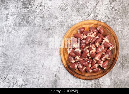 Cœurs de poulet crus sur une planche à découper ronde en bois sur fond gris foncé. Vue de dessus, plan d'appartement Banque D'Images