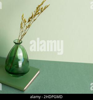 Vase de fleurs sèches et carnet sur table verte Banque D'Images