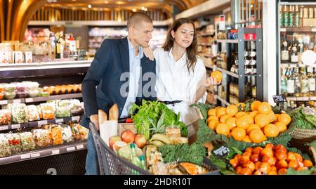 Un jeune couple heureux avec une épicerie dans le supermarché shooses tangerines Banque D'Images