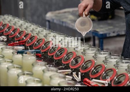 PRODUCTION - 07 décembre 2021, Basse-Saxe, Nesselröden: Un employé verse du stearin dans des bocaux à la Candle Factory.Depuis 2006, Candle Factory produit des bougies à partir de stéarine de culture durable à Eichsfeld, près de Duderstadt.Photo: Swen Pförtner/dpa Banque D'Images