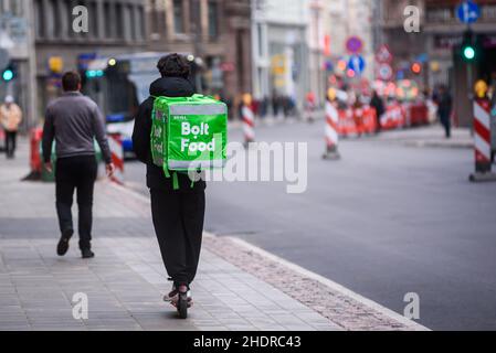 RIGA, LETTONIE.19th octobre 2020.Photo à mise au point sélective.Le préposé à la livraison d'aliments Bolt se déplace avec un scooter. Banque D'Images