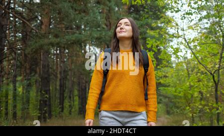 Femme marche le long de la route rurale à travers la forêt verte avec des pins Banque D'Images