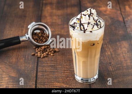 Café glacé et crème fouettée dans une tasse en verre sur une table en bois Banque D'Images