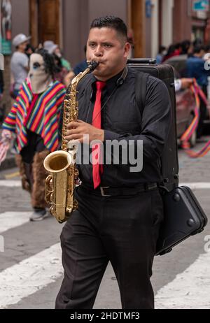 cuenca, Équateur, 24 décembre 2021 - l'homme joue du saxiphone dans le cadre de la parade traditionnelle de la veille de Noël de la Pase del Nino pour enfants en voyage. Banque D'Images