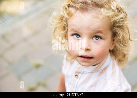 Beau garçon aux yeux bleus et aux cheveux bouclés blonds Banque D'Images