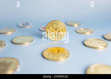 Pièce de monnaie Monero placée au centre parmi un bouquet de pièces de crypto-monnaie sur fond bleu.Bannière avec jeton crypto XMR doré.Gros plan, mise au point douce. Banque D'Images