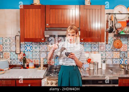 Une femme attirante verse du café percolaté dans une cuisine moderne pour commencer la journée Banque D'Images