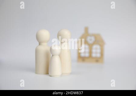 Chiffres de famille sur fond blanc près de la maison.Concept de famille et de maison heureux.Parents et enfants avec espace de copie Banque D'Images